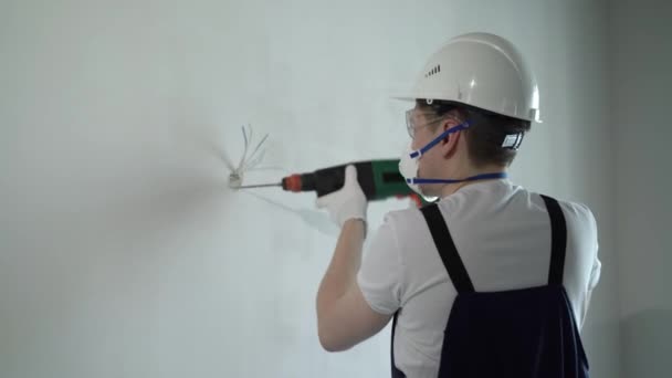 Un trabajador constructor en un sitio de construcción con un puñetazo hace reparaciones a un apartamento o una casa — Vídeos de Stock