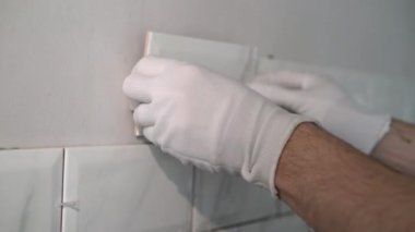 İnşaat alanında çalışan bir inşaatçı yenileme onarımı yapıyor. Duvara fayans seriyorum.