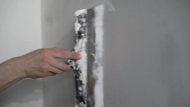 Een bouwvakker doet reparaties in een appartement of gebouw. Zet een stopverf op, maak de muren glad. — Stockvideo