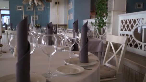 Serverade bord i restaurang för fest. Plattor, glas, gråa servetter. — Stockvideo