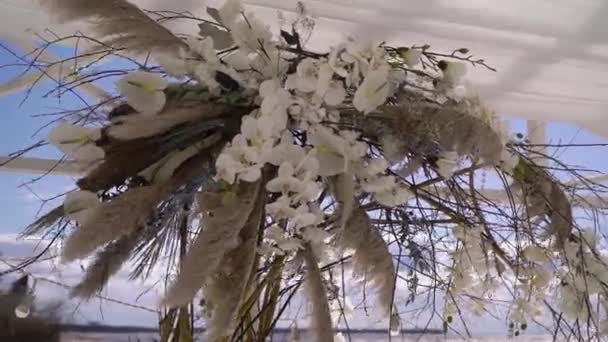 婚礼在海边举行。用白花装饰的小枝拱门. — 图库视频影像
