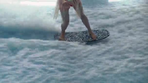 サーファーの女の子は波プールマシンの人工波にサーフボードに乗る. — ストック動画