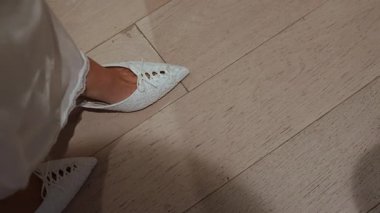 Yakın plan Gelin Ayakkabısı Ahşap zemin üzerinde, sivri uçlu beyaz saten düz dikiz İpek Elbise Hem, Yumuşak Gölge ve Sessiz Hazır Anlık