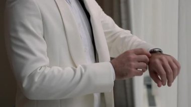 Pencere kenarındaki krem ceketi, pürüzsüz yaka ve kolları gün ışığında düzelten damat koridordan aşağı inmeden önce yansıtıcı bir an oluşturdu.