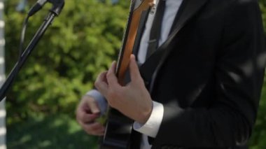Siyah Takım Elbiseli Erkek Gitarist, Mikrofon Yanında Akustik Gitar Çalıyor, Elleri Kapalı ve Parmakları Çalan Akortlar ve Teller,