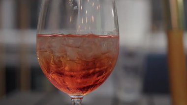 Pembe meşrubatlı, buzlu, buzlu ve köpüklü şarap kadehi. Bulanık şehir siluetine karşı çerçevelenmiş baloncuklar.