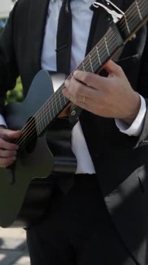 Siyah Takım Elbiseli Erkek Gitarist, Mikrofon Yanında Akustik Gitar Çalıyor, Elleri Kapalı ve Parmakları Çalan Akortlar ve Teller,