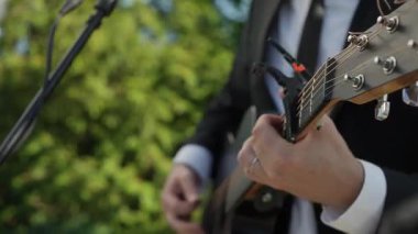 Siyah Takım Elbiseli Erkek Gitarist, Mikrofon Yanında Akustik Gitar Çalıyor, Elleri Kapalı ve Parmakları Çalan Akortlar ve Teller,