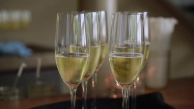 Soluk baloncuklarla dolu köpüklü şarap flütleri, tepsiye yerleştirilmiş kristal bardaklar, sıcak ortam ışığı ve samimi kabul havası, hazır.