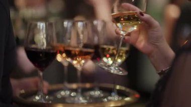 Garson, kalabalık resepsiyonda kırmızı ve beyaz şarap kadehleri taşıyor, misafir elini cama uzatıyor, şık etkinlik servisi...