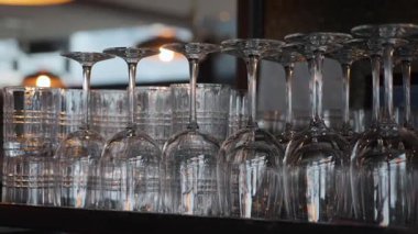 Sıralar dolusu ters çevrilmiş şarap kadehleri, arka planda yumuşak ışık, arka planda tekrarlanan cam ve kaselerin kapatılması, servis sonrası temiz kristal depolama.,