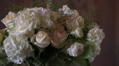 Tahta masadaki beyaz gül buketi, krem rengi ortanca ve yumuşak karamsar ışıkta yemyeşil, yakın plan romantik düğünü çağrıştırıyor.