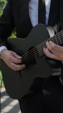 Siyah Takım Elbiseli Erkek Gitarist, Mikrofon Yanında Akustik Gitar Çalıyor, Elleri Kapalı ve Parmakları Çalan Akortlar ve Teller,