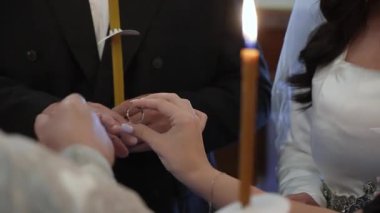 Yakından Gelinimiz, damadın parmağına altın yüzük takıyor. Mum alevi, mihrapta yeminler ve dualar, eller ve bando.