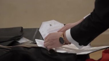 Damat yüzük kutusunu takım elbiseli çantaya koyup görünür, dikkat et, dokuyu katla ve aksesuarları düzenle, seyahat hazırlıkları...