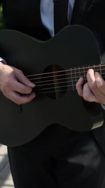 Siyah Takım Elbiseli Erkek Gitarist, Mikrofon Yanında Akustik Gitar Çalıyor, Elleri Kapalı ve Parmakları Çalan Akortlar ve Teller,