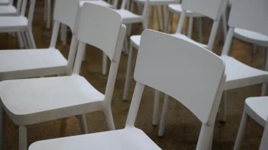 Sıralardaki Boş Beyaz Sandalyeler, Minimalist Olay Alanı Ahşap zemin ve Yumuşak Yanlı Işıklar, Kapalı Açılar Simetri ve Doku Vurgusu