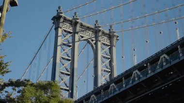 Manhattan Köprüsü, Dumbo 'daki tuğla cepheleri tarafından çerçevelenmiş, süslenmiş kemer ve süspansiyon kabloları dar sokaklar arasında yükseliyor, desenli mason...