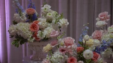 Pastel Düğün Çiçeği Masada, Yumuşak Pembe Güller, Fildişi Ortancalar, Mavi Delphinium ve Yeşillik Süslü Vazoda, Örtülü