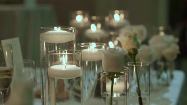 Mum ışığında akşam yemeği için hazırlanan masa örtüsü, uzun silindirlerde yüzen mumlar, köpüklü şampanya flütleri ve su bardakları,