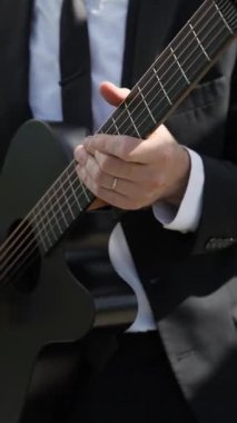 Siyah Takım Elbiseli Erkek Gitarist, Mikrofon Yanında Akustik Gitar Çalıyor, Elleri Kapalı ve Parmakları Çalan Akortlar ve Teller,