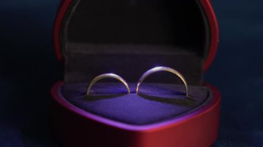 Kırmızı Kutuda Altın Alyanslar Kadife Yastığın İçindeki Yumuşak Mor Işıkla aydınlatılıyor, Yavaş Açılış Kamerası Çapraz Cilalanmış Gruplar,