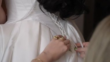 Nedime Dantelli Korse Fildişi Elbise Kapanışı, Narin Parmaklar Kurdele Düğümleri, Altın Yüzükler ve Saten Kumaş Gelinlikte Görünür