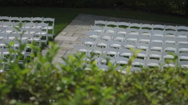 Beyaz Sandalyeler Yeşil Çit boyunca parlıyor Taş Koridoru boyunca, Ön Yaprak Bulanık, Boş Oturma Sıraları Manikürlü Çimenlikte, Gölgeli Geç Kalan