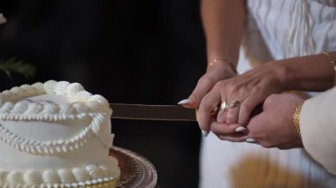 Beyaz Düğün Pastasını Birlikte Kesen Çiftler, Elleri Bıçakla Kapalı, Altın Yüzükler Parıldıyor, Kremalı Boru Şekerleme ve Çiçek Aksanları