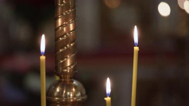 Süslü pirinç tezgahında parlak mum kümeleri, çoklu yanıp sönen alevler Kilisede yansıtıcı ışıltı ve Bokeh ışıkları oluşturur