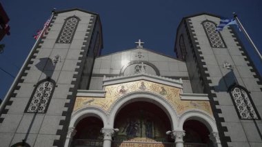 Altın Mozaikler, Üçlü Kemerler, İkiz Çan Kuleleri ve Derin Mavi Gökyüzü Altında Dalgalanan Bayraklar ile Güneş Işığı Ortodoks Kilisesi Yüzü