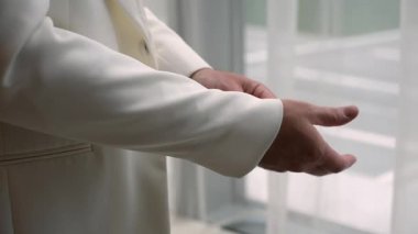 Pencere kenarındaki krem ceketi, pürüzsüz yaka ve kolları gün ışığında düzelten damat koridordan aşağı inmeden önce yansıtıcı bir an oluşturdu.