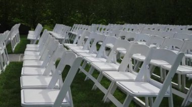 Açık hava düğün seremonisi, düzenli düzenleme ve tekrarlayan şablonlar için çimenlikteki boş beyaz katlanır sandalyeler sükunet oluşturur