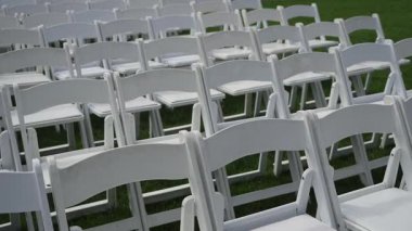 Açık hava düğün seremonisi, düzenli düzenleme ve tekrarlayan şablonlar için çimenlikteki boş beyaz katlanır sandalyeler sükunet oluşturur