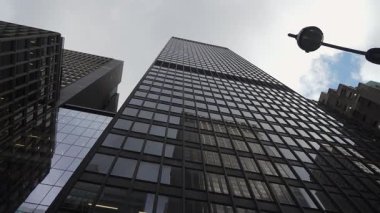 Aşağıdan Yakaladığımız Kederli Cam Yüzü, Bulutları Yansıtan Grip Gibi Pencereler, Çerçevedeki Metal Lamba Postası, Emlakçı İzciliği