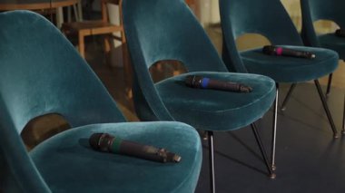 NEW YORK, ABD - 4 Ekim 2025: Sahnede Mikrofonlu Boş Teal Sandalyeleri, Kadife Döşemeler ve Siyah Metal Bacaklar, Renkli Mikrofon Halkaları Koltuklara Dinleniyor, Modern Konferans