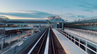 Tren raylarından bakıldığında modern havaalanı yapıları ve aşağıdaki yoğun trafiğin alacakaranlık saatlerinde dinamik kentsel çevreyi yakaladığını görüyoruz.