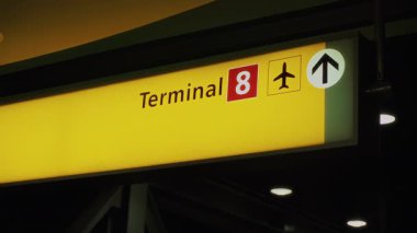 Havalimanı aydınlatmalı. Terminal 8 'de uçak sembolü ve yukarı doğru ok işareti var. Geceleri modern havaalanı çevresindeki yolculara rehberlik ediyor.