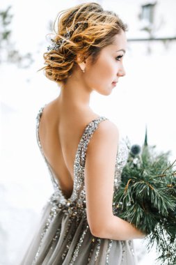 Gelinlik cadısı kış mevsiminde açılır. Saçını kestirmiş bir gelin, gri bir gelinlik içinde çam ağaçlarıyla karlı bir yamaçta duruyor. Noel düğünü konsepti. Seçili odak.