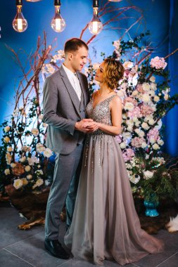 Düğün çifti kış dekorunun arka planında poz veriyor. Güllerin ve dalların arkaplanı yeni yıl tarzında. Seçili odak. Bulanık arkaplan