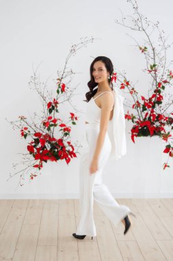 Şık ve zarif bir takım elbise içinde yürüyen esmer bir gelin. Pantolonlu bir gelinlik, modern tarzda. Kadın akşam ekipmanları, kutlama için kıyafet..