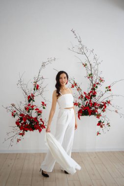 Beyaz pantolonlu, modaya uygun bir gelin. Kırmızı noktalı kemer seremonisi. Düğün kış mevsiminde.