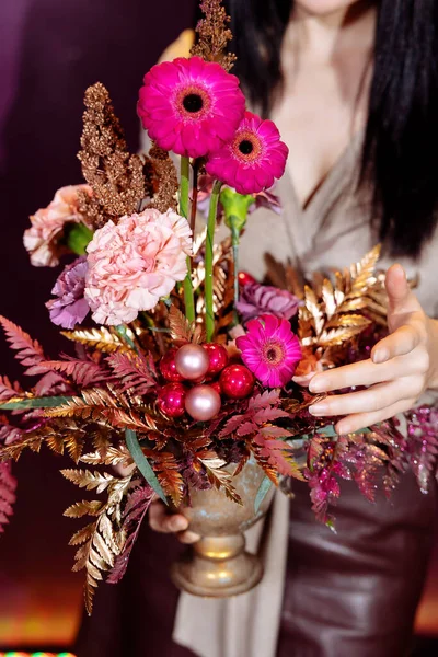 florist woman holds a flower arrangement of pink gerbera and white carnations in her hands.Selected focus and blurred background