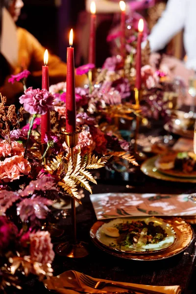 圣诞婚宴上桌了 金黄色的新叶 粉色和红色的花和金色的盘子 金属烛台上的蜡烛 选定的重点和模糊的背景 — 图库照片