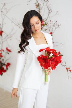 Beyaz pantolonlu, modaya uygun bir gelin. Kırmızı noktalı kemer seremonisi. Düğün kış mevsiminde.