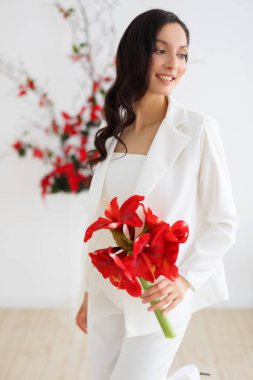 Beyaz pantolonlu, modaya uygun bir gelin. Kırmızı noktalı kemer seremonisi. Düğün kış mevsiminde.