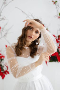 Beyaz puantiyeli güzel bir gelinin moda portresi. Bir tören için taze çiçeklerin oluşturduğu arkaplan.