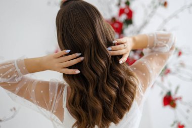 Kız model esmer saçlarını tutuyor. Düğün ve akşam şekillendirmesi ve kuaförlüğü