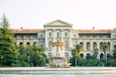 SOCHI, RUSSIA NOVEMBER 16, 2019: Günbatımında tropik ormanın ortasında Ordzhonikidze 'den sonra terk edilmiş sanatoryum. Çeşmenin manzarası ve ağaçların arasındaki ana bina.