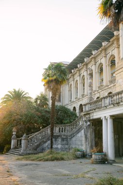 SOCHI, RUSSIA NOVEMBER 16, 2019: Günbatımında tropik ormanın ortasında Ordzhonikidze 'den sonra terk edilmiş sanatoryum. Taş merdiven ve kemer pencereleri görünüyor. Düğün için romantik bir yer.